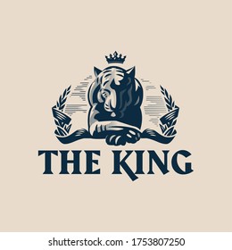 A calm and balanced tiger with a crown lies with its paw on its paw. Around him is a laurel wreath encircled by a ribbon. Vector illustration.