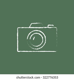 Camera hand drawn in chalk on a blackboard vector white icon isolated on a green background.