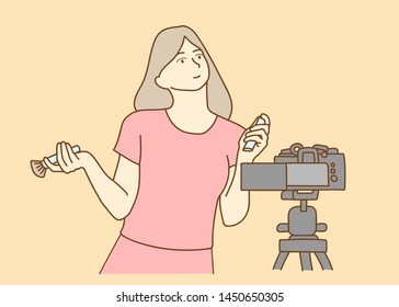 Camera recording a young female blogger reviewing cosmetic products while making a video