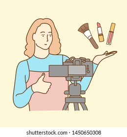 Camera recording a young female blogger reviewing cosmetic products while making a video