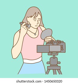 Camera recording a young female blogger doing makeup while making a video