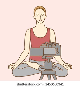 Camera recording a young female blogger doing yoga while making a video