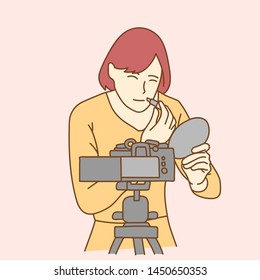 Camera recording a young female blogger doing makeup while making a video