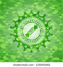candy icon inside green emblem with triangle mosaic background