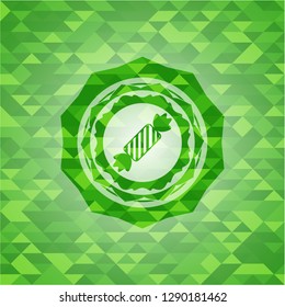 candy icon inside green emblem. Mosaic background