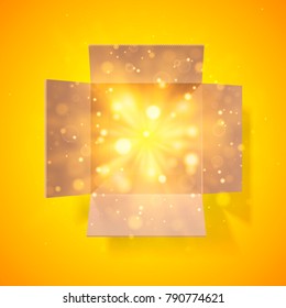 Cardboard box with a bright glow inside. Open box. Top view. Detailed bokeh effect.