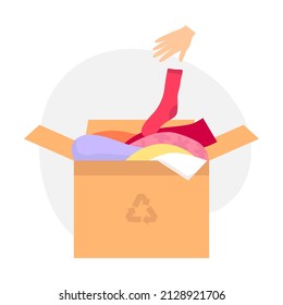 Caja de cartón con ropa antigua para reciclaje de ropa. La mano arroja el calcetín dentro de la caja. El concepto de reciclaje de ropa, donaciones. Ilustración de color del vector aislada en fondo blanco