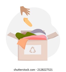 Cardboard box with old clothes for recycling. Black hand throws the sock into the box. The concept of clothing recycling, donations. Vector color illustration isolated on white background 