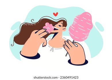 Carefree woman eats cotton candy, walking in park and enjoying sweet taste of street dessert. Girl holds pink cotton candy on stick, experiencing bliss and surge of positive emotions