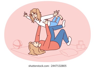 Caring mother lying on floor lifts laughing daughter enjoying playing with child on long-awaited day off. Carefree Caucasian family from mom self raising daughter or babysitting woman