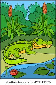 Cartoon animals for kids. Little cute alligator stands near the lake and smiles.