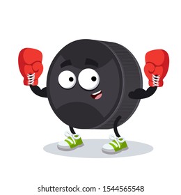 cartoon black rubber hockey puck mascot in red boxing gloves on white background
