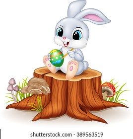 Cartoon Easter Bunny painting an egg on tree stump