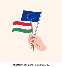 Cartoon Hand Holding European Union And Hungarian Flags. EU Hungary Relationships. Concept of Diplomacy, Politics And Democratic Negotiations. Flat Design Isolated Vector