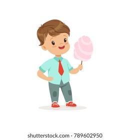 Cartoon little boy standing and holding big stick of cotton candy. Kid with cheerful face expression wearing casual clothes blue shirt and jeans. Flat vector design