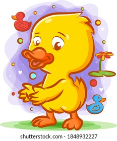 The cartoon of a little yellow duck dancing on the green grass with the happy face