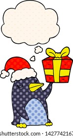 cartoon penguin with christmas present with thought bubble in comic book style