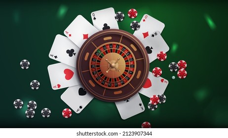 Casino roulette on green table with poker chips and playing cards, top view. Background for your arts