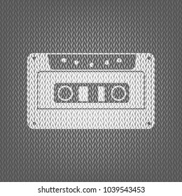 Cassette icon, audio tape sign. Vector. White knitted icon on gray knitted background. Isolated.