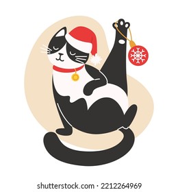Cat in a Santa hat is playing wits a Christmas decoration