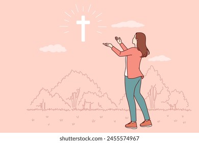 Catholic woman looks at cross glowing in sky, praying to god for help in finding right path. Sign from god in form of christian crucifix and believing girl looking in surprise at miracle