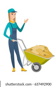 Caucasian builder standing near wheelbarrow full of sand. Full length of young female builder waving her hand near wheelbarrow with sand. Vector flat design illustration isolated on white background.