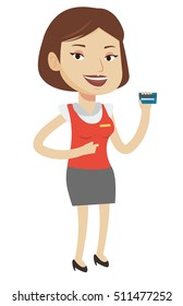 Caucasian female cashier holding credit card. Happy female cashier at work. Smiling cashier pointing with her finger at credit card. Vector flat design illustration isolated on white background.