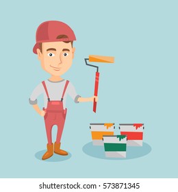 Caucasian house painter in uniform holding paint roller in hands. Young cheerful house painter at work. Smiling house painter standing near paint cans. Vector flat design illustration. Square layout.