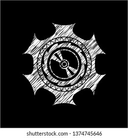 CD or DVD disc icon inside chalkboard emblem on black board