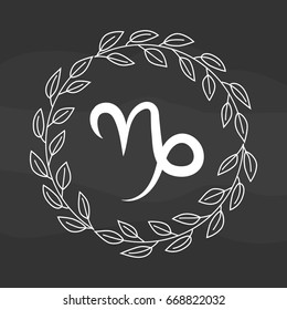 Chalk drawing flat capricorn symbol in rustic floral wreath