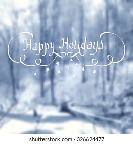 Chalk drawn calligraphy ''Happy Holidays'' on winter blurred background. Happy Winter theme.