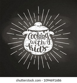 Chalk silhoutte of boiling pan with sun rays and lettering - Cooking with kids - on blackboard. Good for cooking logotypes, bades, menu design or posters.