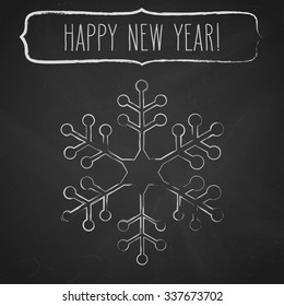 Chalk snowflake and a frame with New Year greetings over black chalkboard.