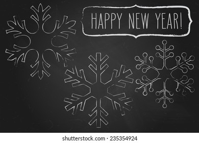 Chalk snowflakes and a frame with New Year greetings over black chalkboard.