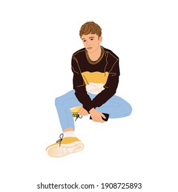 Character teenager sitting with a phone in his hands. A sad guy sits thoughtfully. Bullying among youth. Youthful maximalism. Male character of a young man. A guy in jeans, a jumper and sneakers.