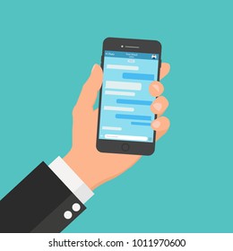Chatting and messaging on mobile phone. Hand holding a smartphone with opened messenger app window.