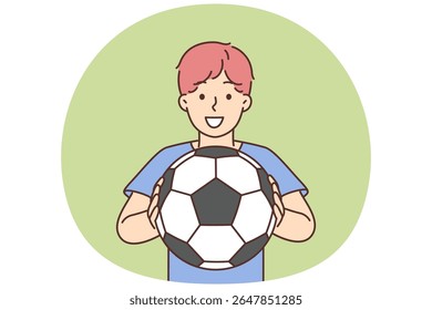 Cheerful boy of school age holding soccer ball and smiling offers to play football. Positive boy football player dreams of becoming professional sportsman and participating in premier league