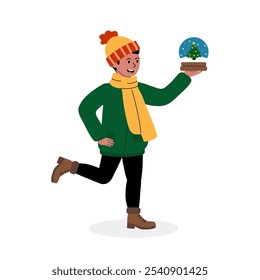 Uma criança alegre carregando um globo de neve com uma árvore enquanto usa roupas de inverno