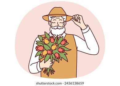 Alegre anciano sostiene ramo de flores de primavera toques sombrero en el saludo para el concepto de la vejez feliz. Hombre canoso positivo con bigote y barba sostiene tulipanes de flores cultivados en su propio jardín