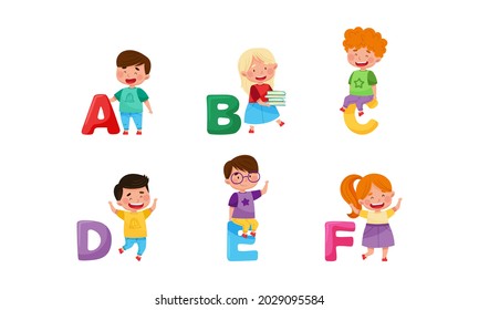 Cheerful Kids Standing with Big Alphabet Letters Vector Set