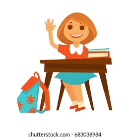 Cheerful little girl sits at desk in school