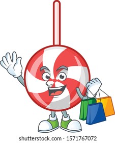 Cheerful striped peppermint candy cartoon character waving and holding Shopping bags