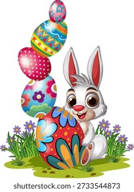 A cheerful white rabbit sits in grass beside a tall stack of decorated Easter eggs