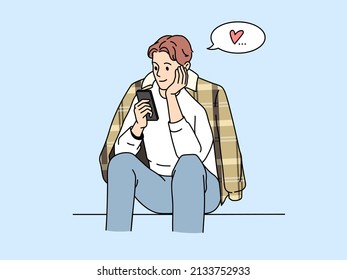A cheerful young man gives a loving heart to a social network. The guy sits and dreams of love. The concept of new acquaintances.