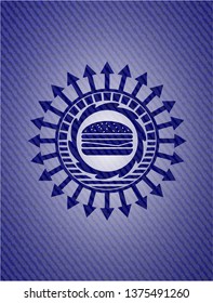 cheeseburger icon inside emblem with jean background