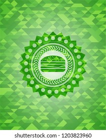 cheeseburger icon inside green emblem with mosaic ecological style background