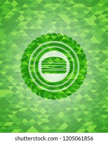 cheeseburger icon inside green emblem. Mosaic background