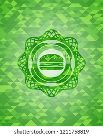 cheeseburger icon inside green emblem with mosaic background