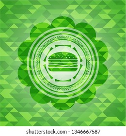 cheeseburger icon inside green emblem with mosaic ecological style background