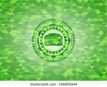 cheeseburger icon inside green emblem with mosaic ecological style background